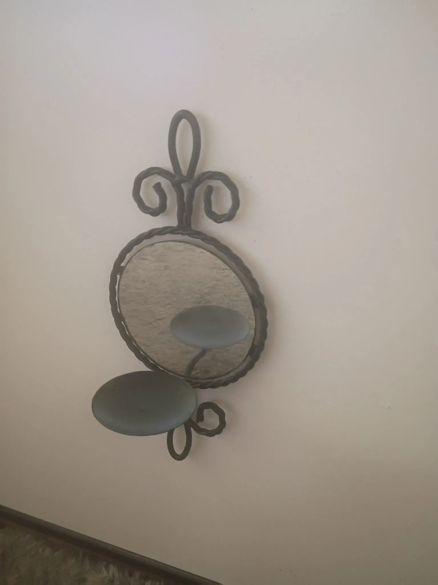 Wall sconce after refinishing: matte black scrollwork frame with round mirror