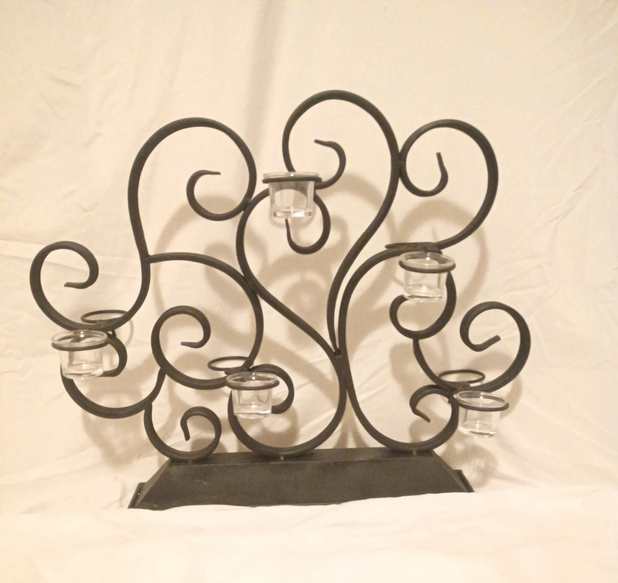 Scrollwork candelabra after refinishing: matte black iron with glass votive cups